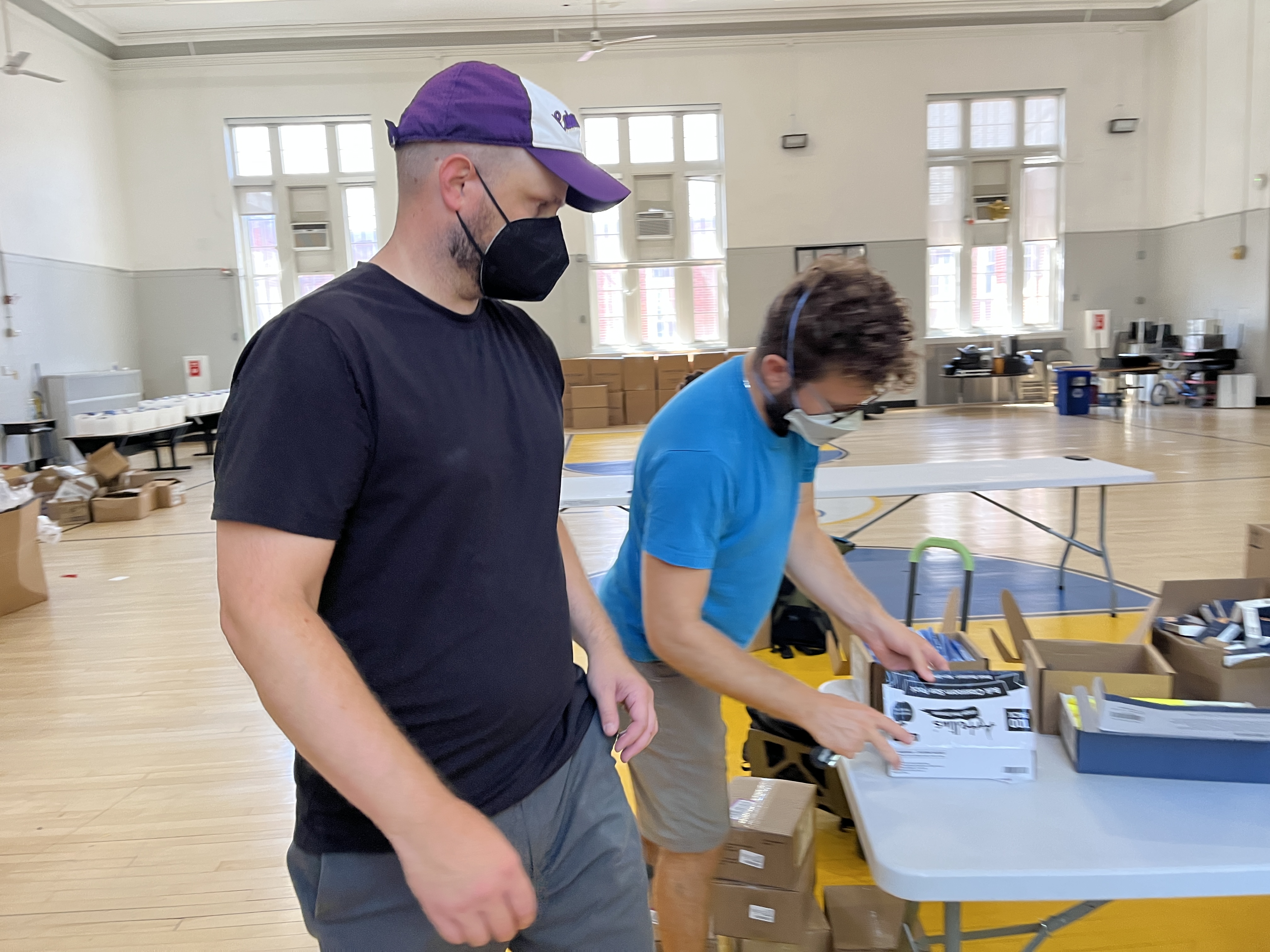 Robert, masked, at table packing school supplies with another volunteer